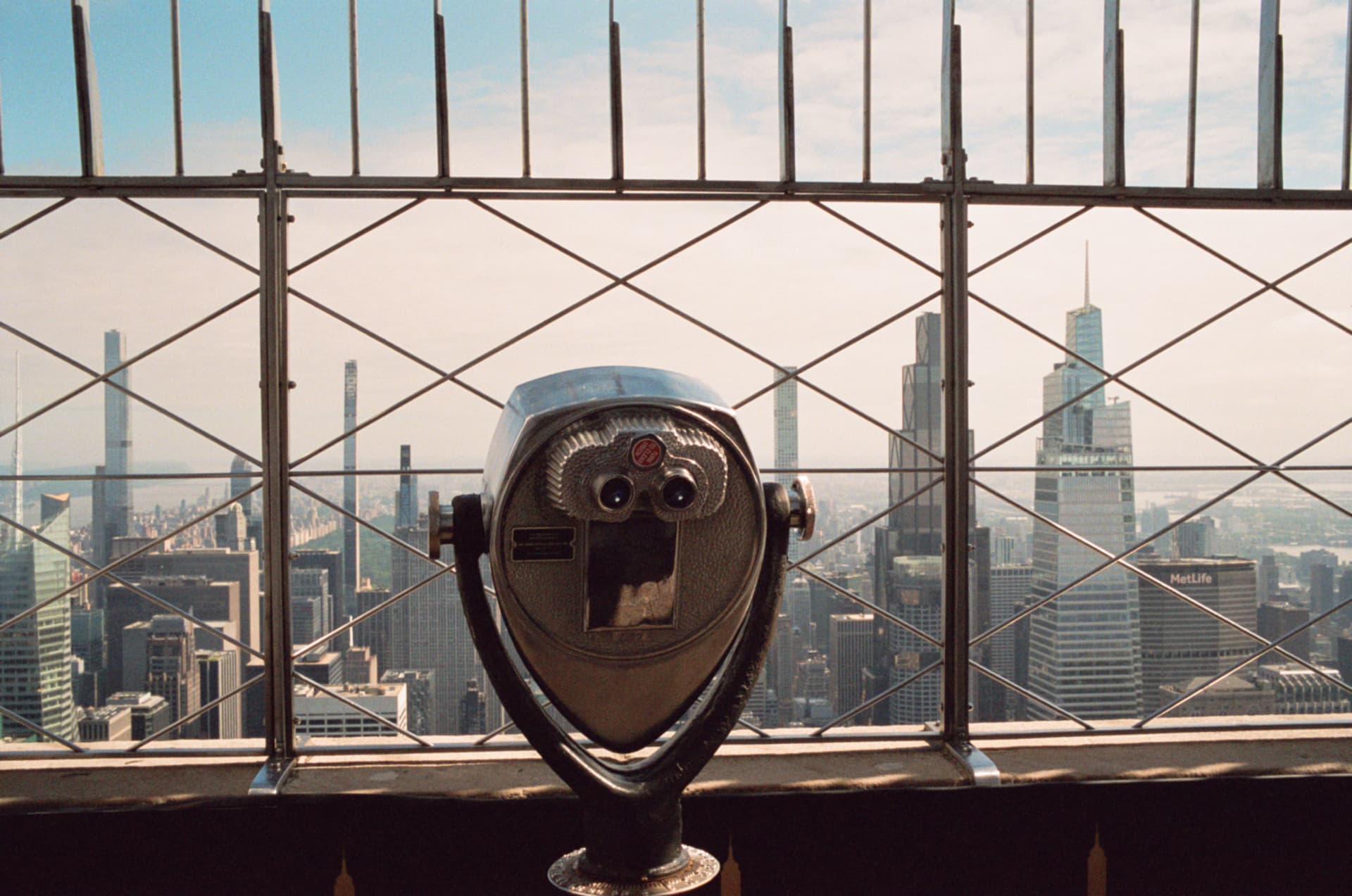 Coin-operated viewfinder overlooking the Manhattan skyline through a metal railing