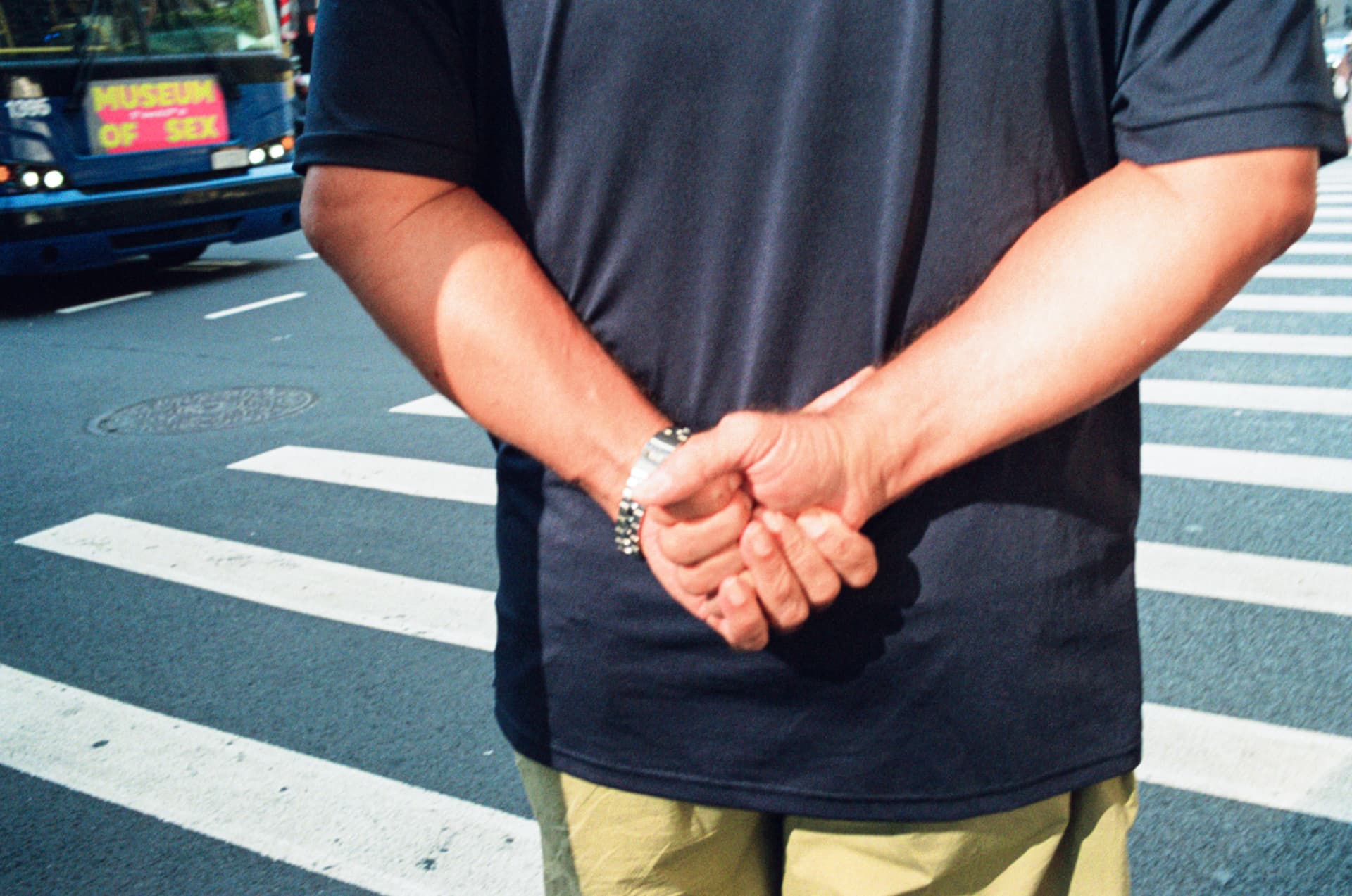 Man standing with hands behind his back near a Museum of Sex ad